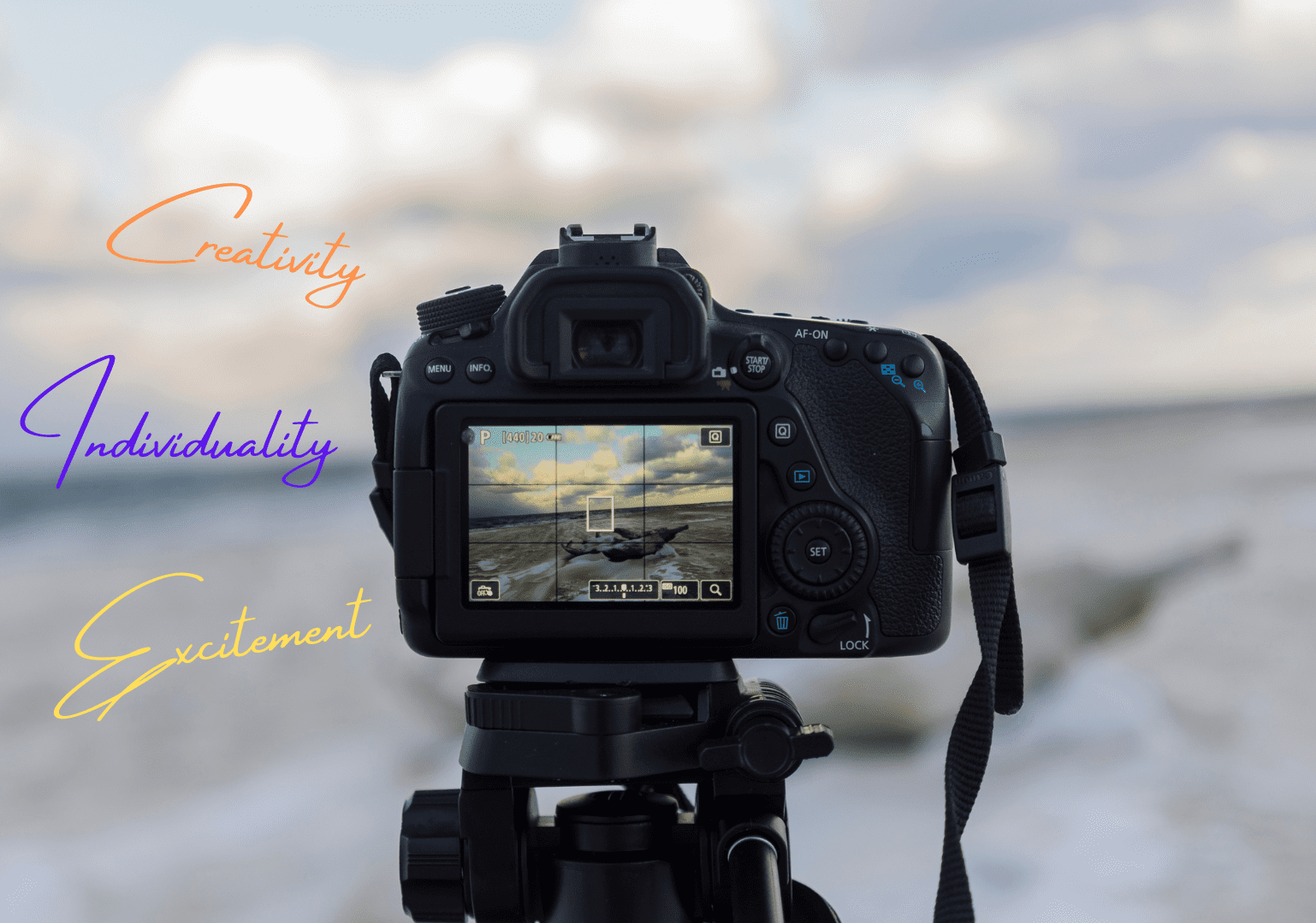 Fotokamera und Schrift vor Strand mit Wolken